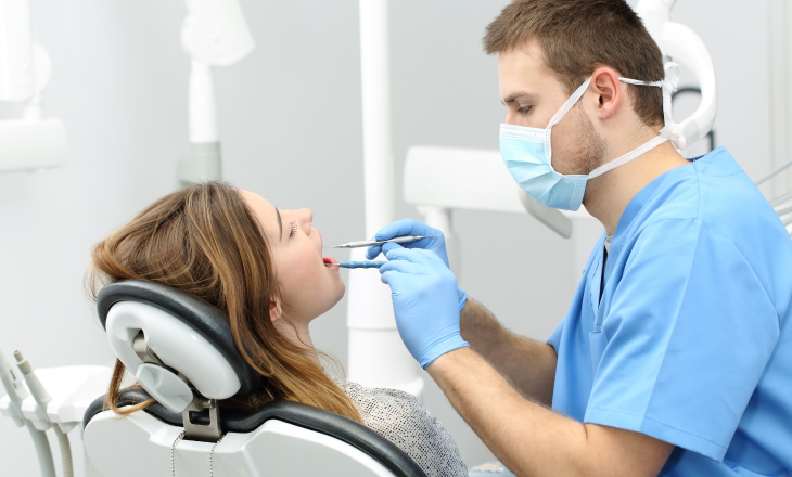 Male Dentist Examining Woman's Teeth