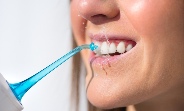Woman Spraying Between Teeth by Water Flosser